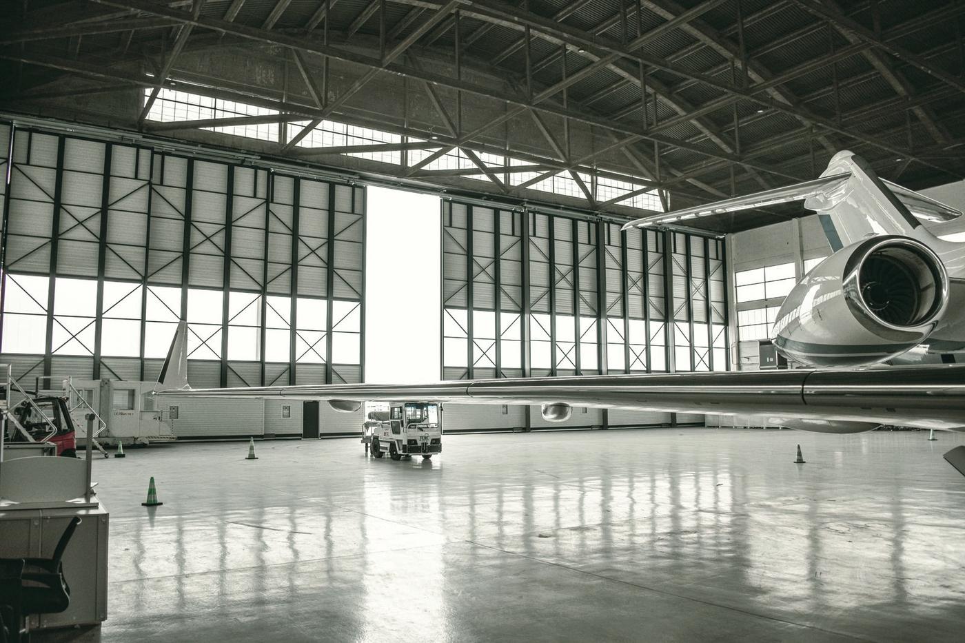 A business jet tail positioned inside a working operator hangar